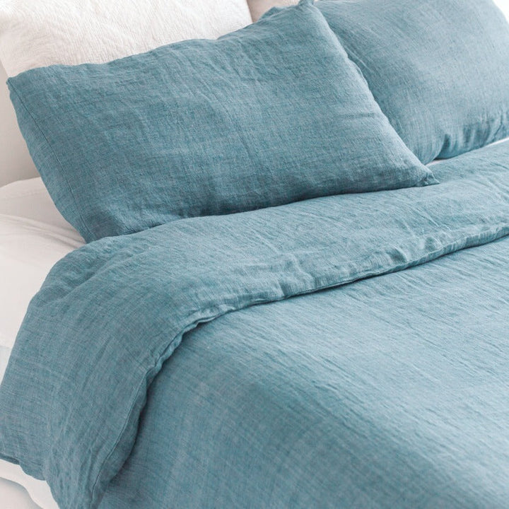 Denim blue linen duvet cover set, made from Belgian flax, shown on a bed for natural temperature regulation.