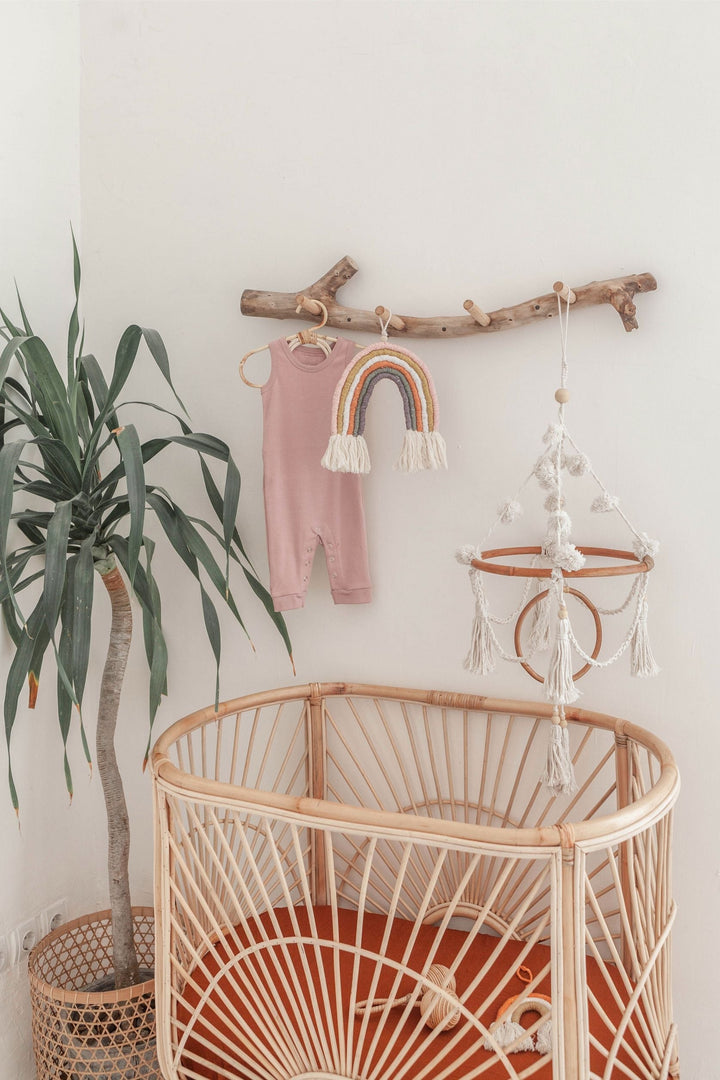 Organic cotton pom pom baby mobile with rattan ring hanging over a crib in a natural-themed nursery setting.