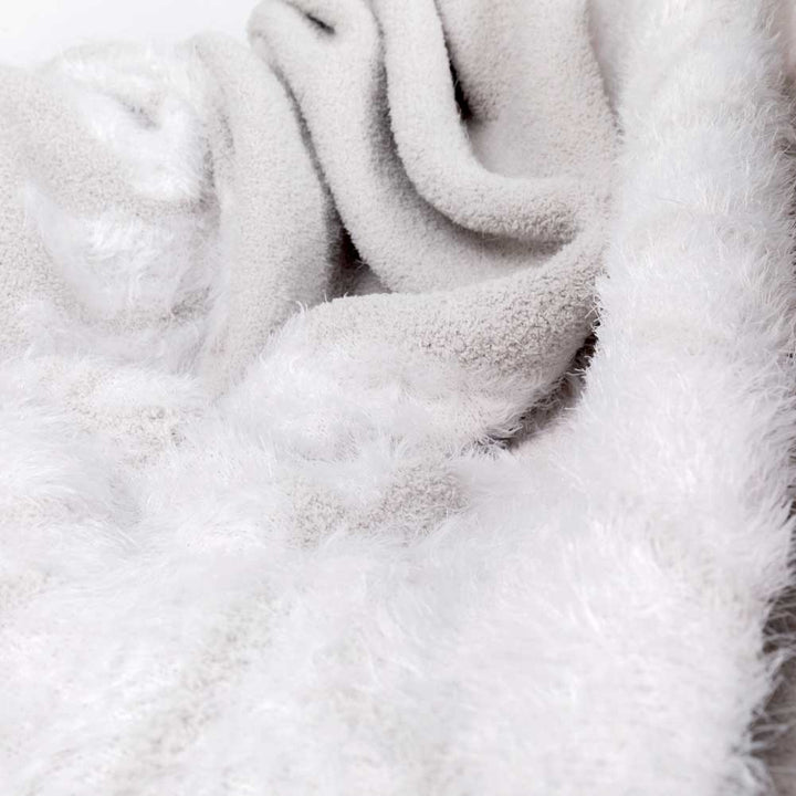 Close-up of a luxurious Dream Wings Silver blanket with fluffy feathered texture, soft microchenille knit. Ideal for a cozy embrace.