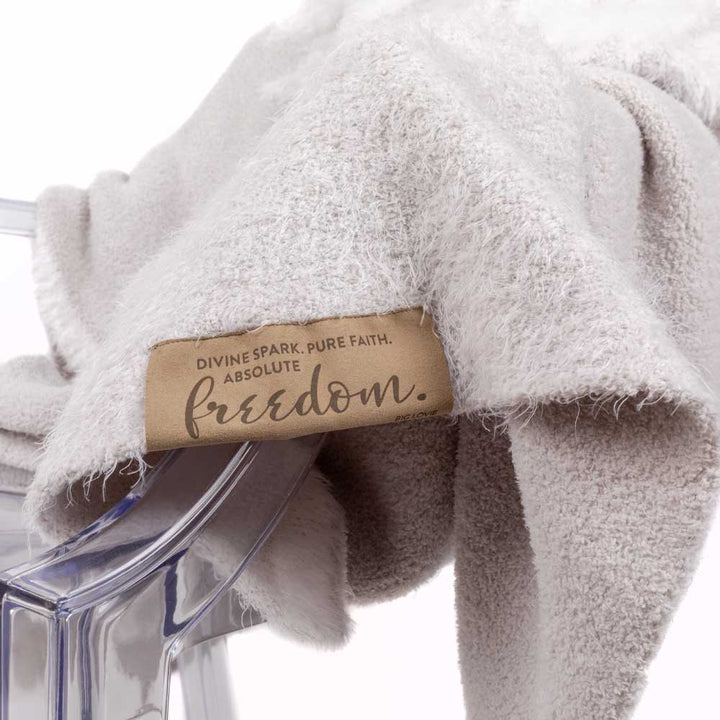 Luxury Dream Wings Silver blanket with fluffy texture and "freedom" label, showcasing soft microchenille and feather yarn blend.