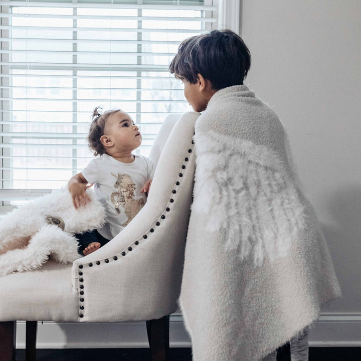 Two children with Dream Wings Luxury Blanket in feathered fluff design, soft and airy, perfect for comfort and warmth.
