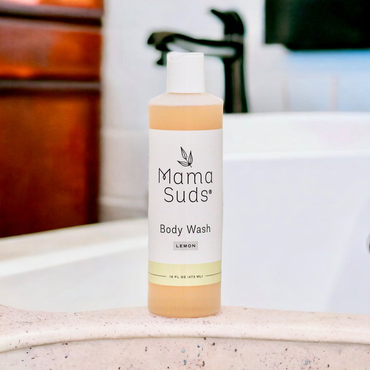 Plant Based Body Wash with Lemon scent on bathroom counter, natural ingredients including saponified olive oil, in a 16 fl oz bottle.