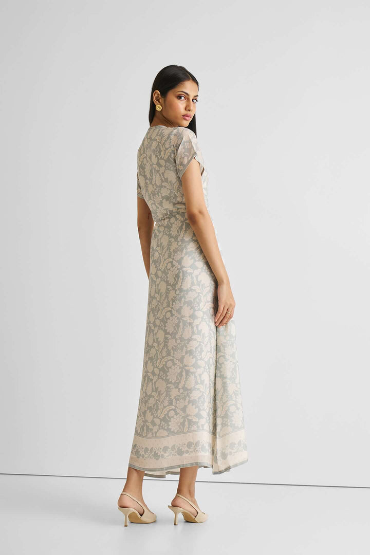 Woman wearing a blue floral maxi wrap dress, showing the back design in a studio setting.
