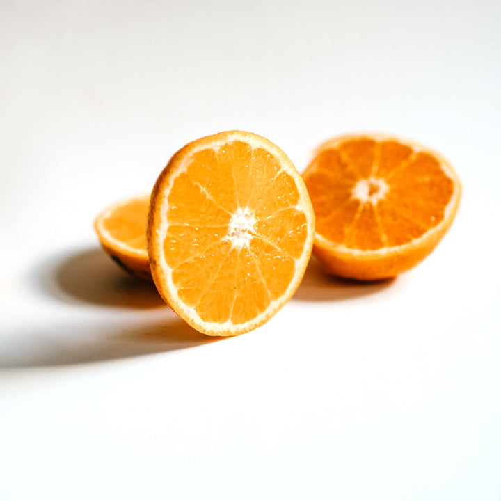 Sliced orange on white background, highlighting fresh citrus used in vitamin C skincare products for brightening and even skin tone.