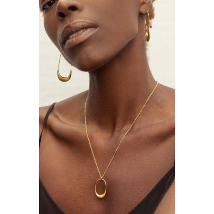 Woman wearing Delicate Mezi Brass Pendant Necklace with organic charm, handcrafted in Kenya. Elegant everyday accessory.