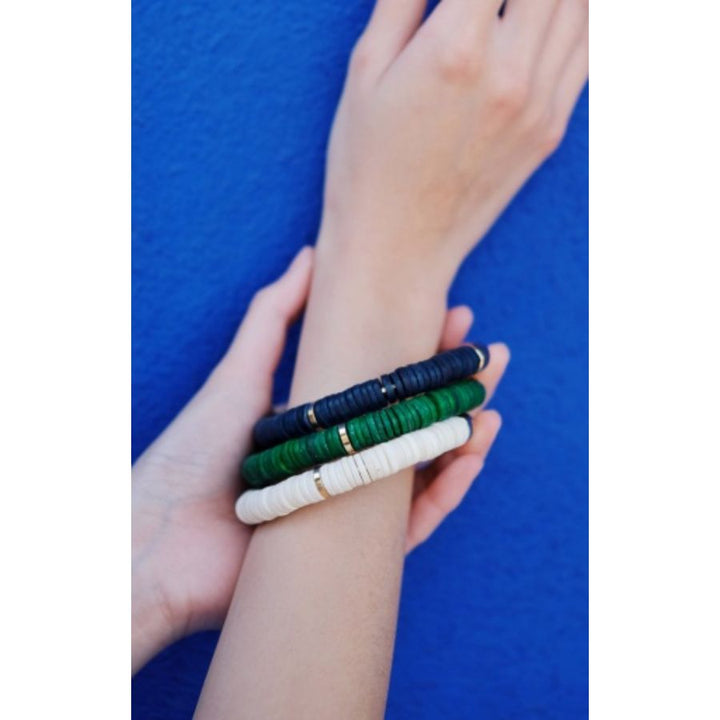 Person wearing Karamu Statement Bangle in gold and white, made of ethically sourced bone, 24k gold plated brass, handcrafted in Kenya.