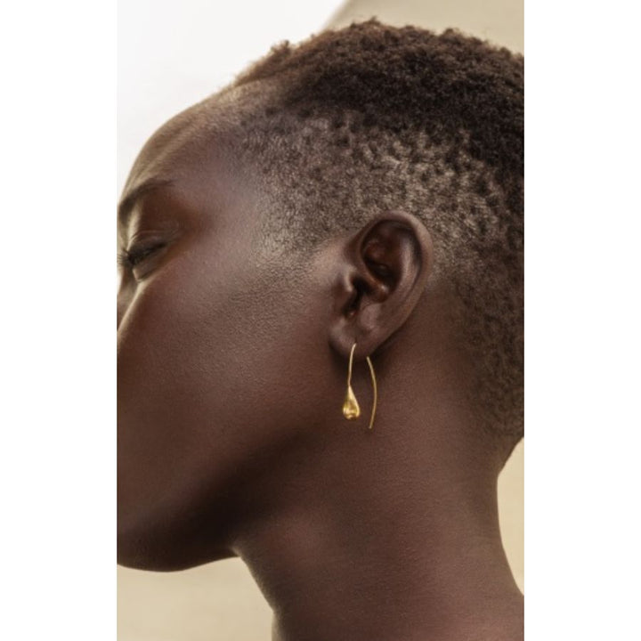 Close-up of model wearing Dash Threader Drop Earrings made from recycled brass, showcasing elegant arc design.