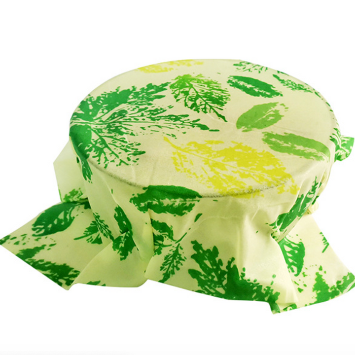 Reusable beeswax food wrap covering a bowl, featuring green leaf design for eco-friendly kitchen use, set of 3 assorted sizes.