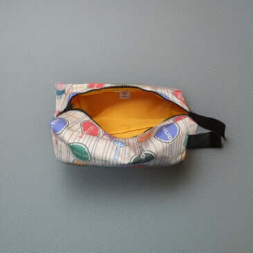 Logo Pattern Dopp Kit with colorful design, open to reveal its spacious yellow interior, perfect for travel essentials.