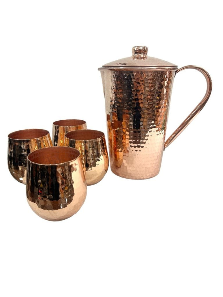 Hammered copper pitcher with lid and four tumbler set, shiny finish, elegant tableware for home or gifting.