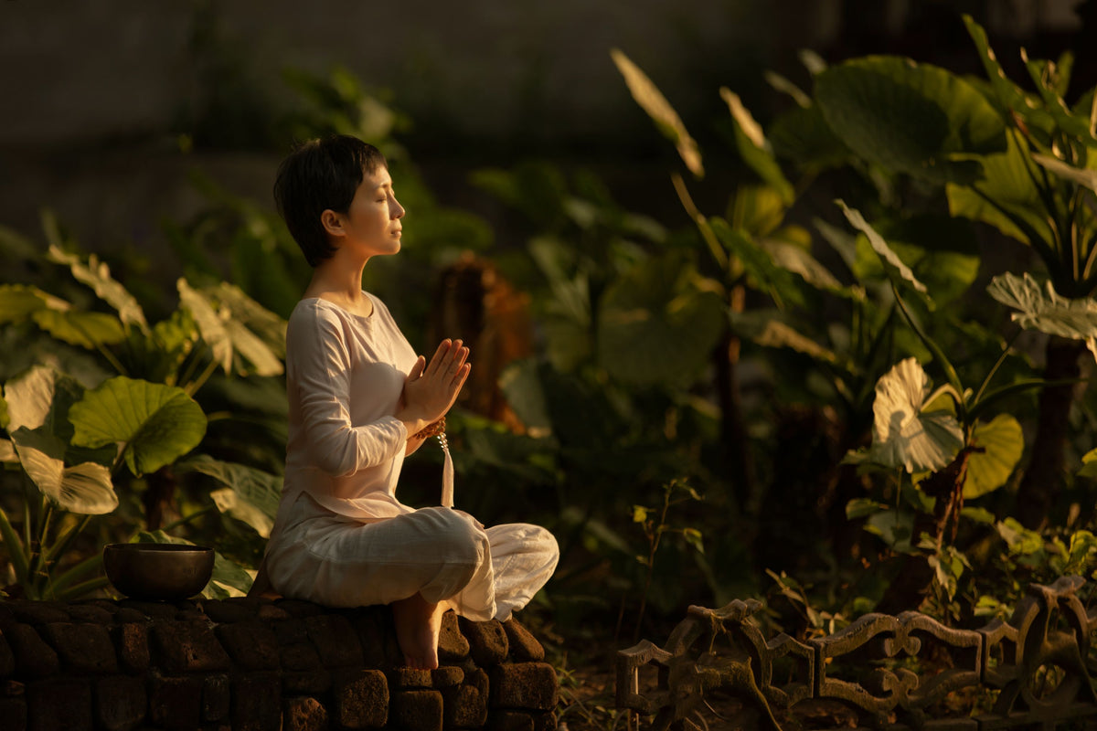A woman meditating in a garden at golden hour