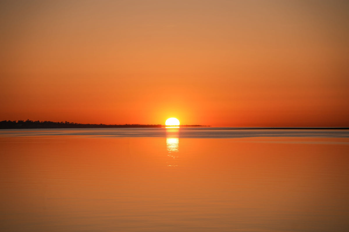 Calm ocean sunrise with golden reflection