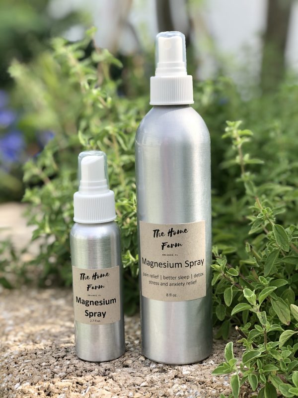Two bottles of magnesium spray placed outdoors surrounded by greenery, promoting holistic wellness and natural muscle relaxation.