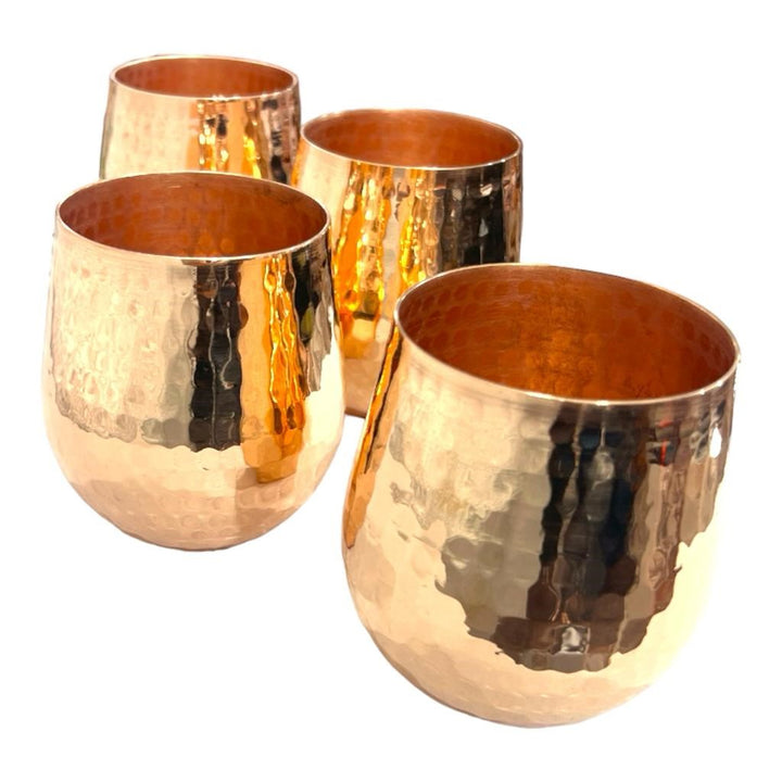 Four hammered copper tumblers with a shiny finish, each with a 3.35" diameter and 3.75" height, displayed against a white background.