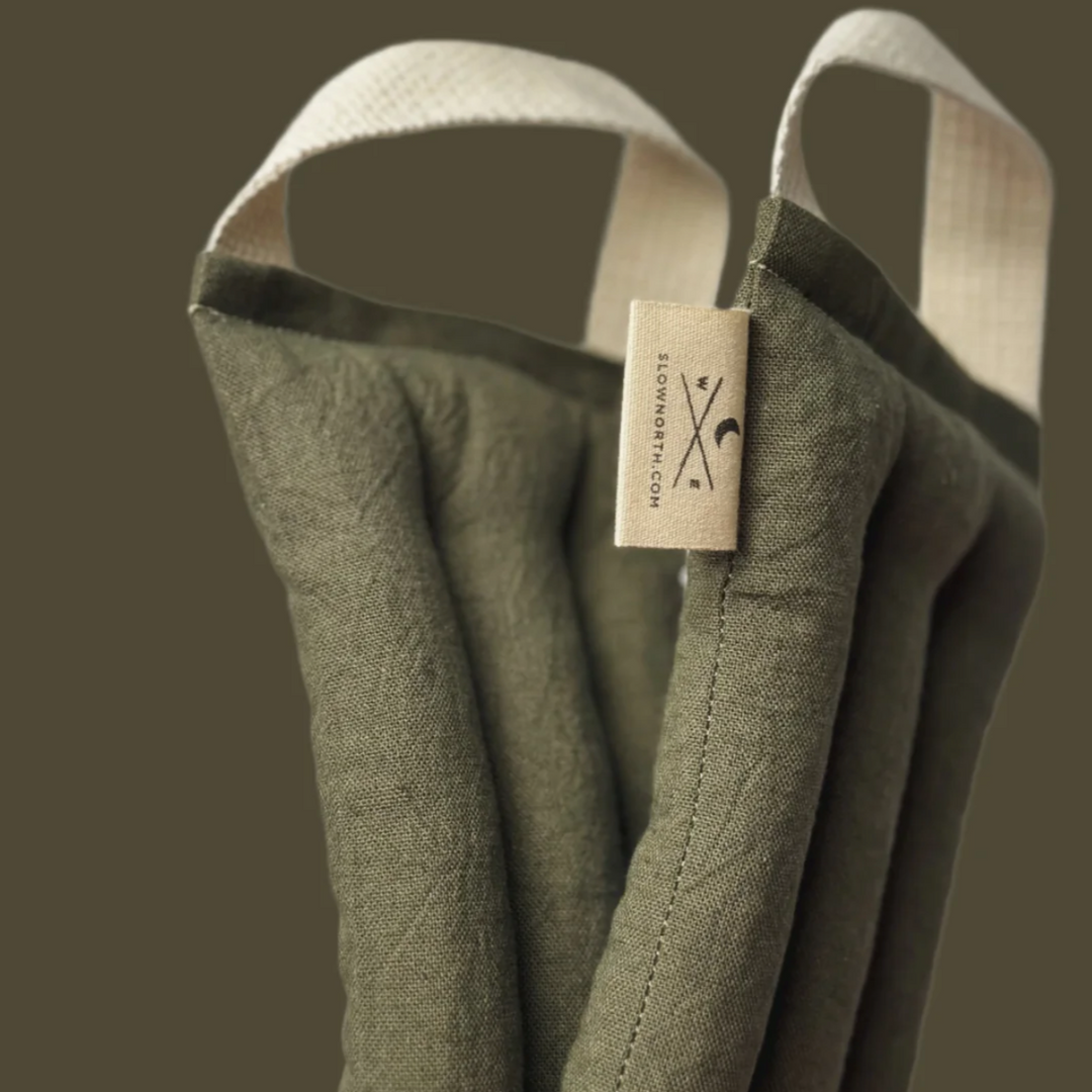 Close-up of a green padded neck cushion with white handles, part of a sleep and fitness collection.