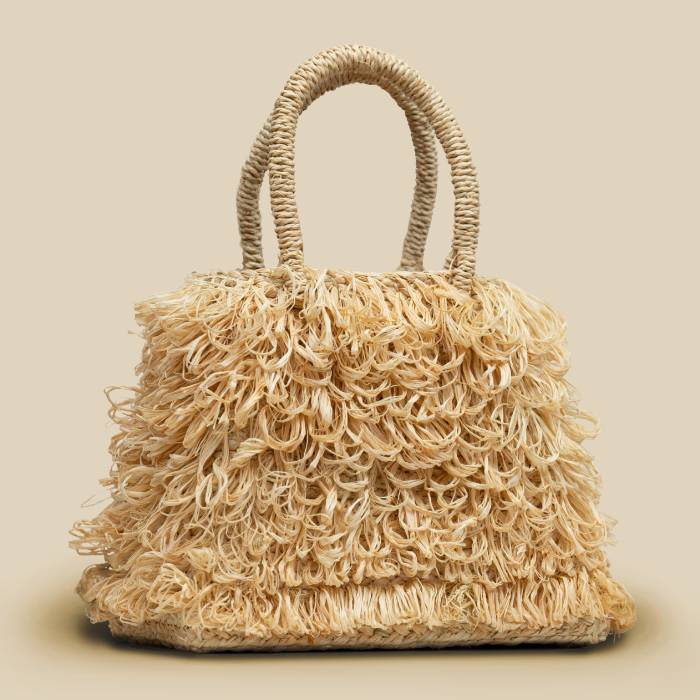 Handwoven raffia loop bag with circular handle details and natural palm fiber texture in earthy neutral tone