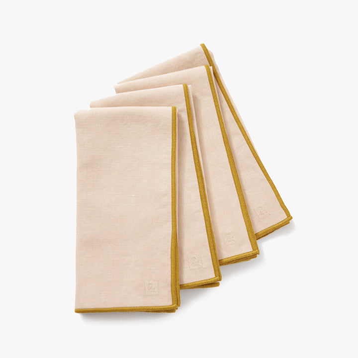 Oat colored cotton linen blend cloth dinner napkins folded on wooden table with ceramic plates