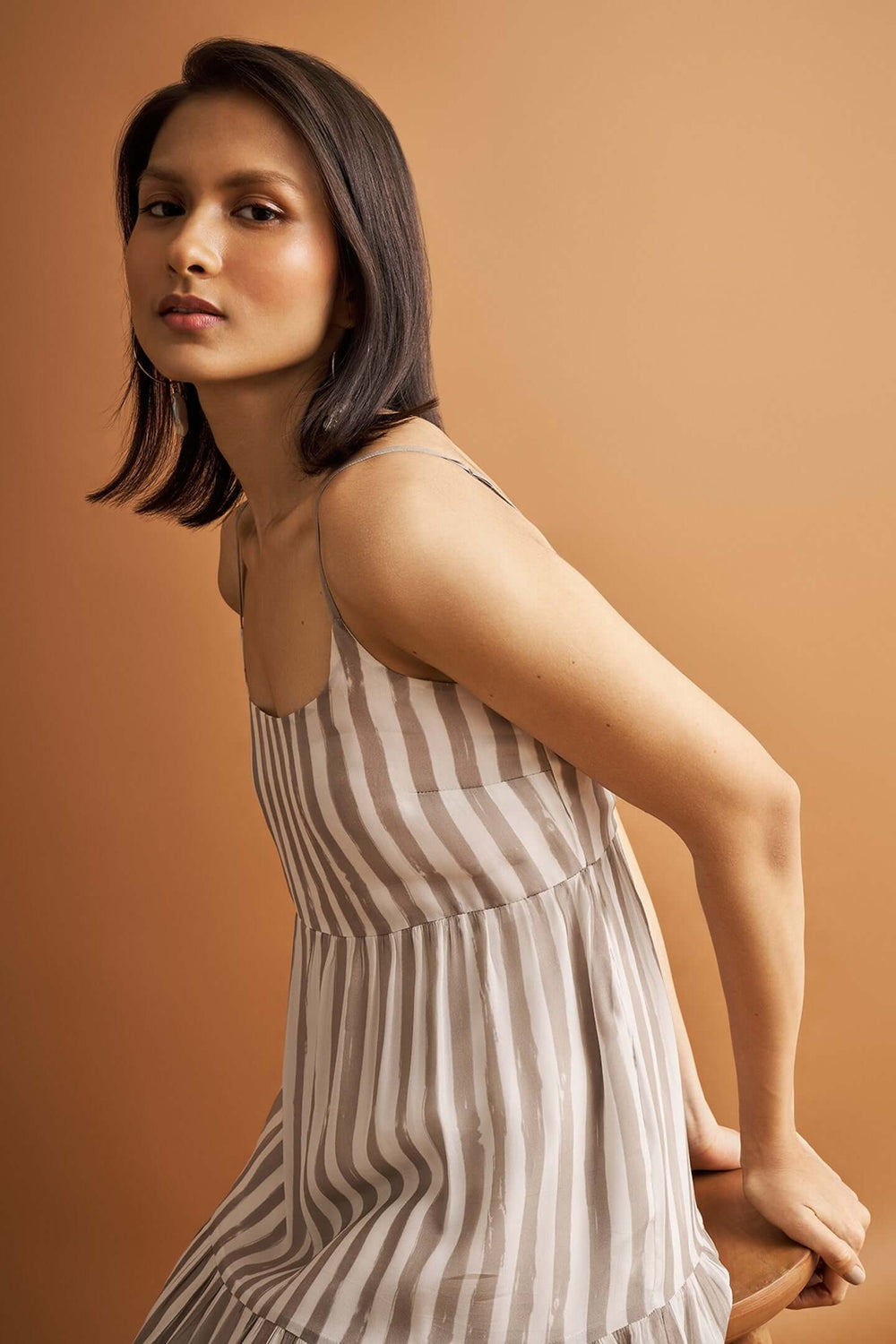 Beige striped tiered maxi dress with adjustable straps and flowing silhouette on model