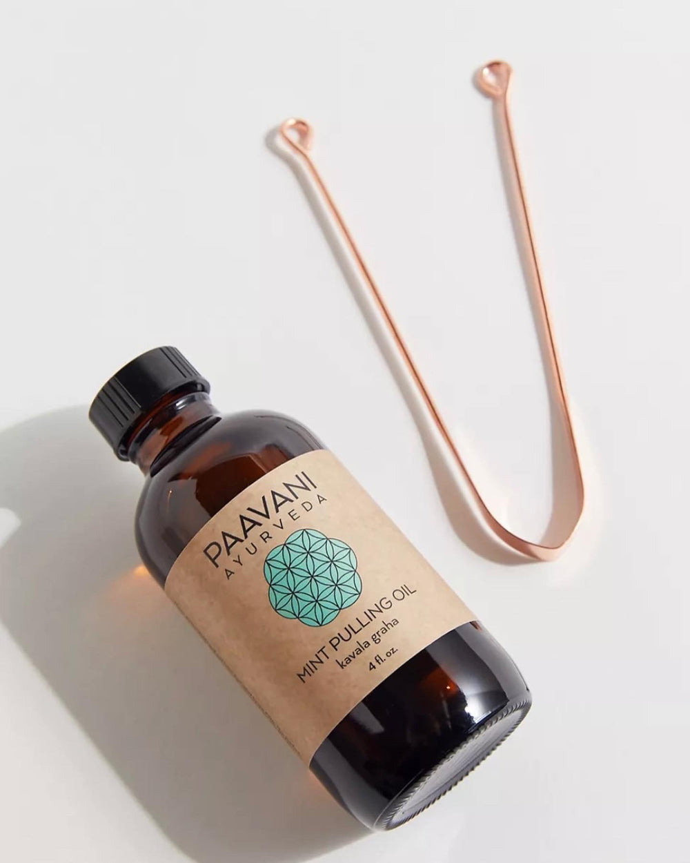 Ayurvedic oral care ritual with mint oil pulling bottle and copper tongue cleaner for improved digestion and gum health.