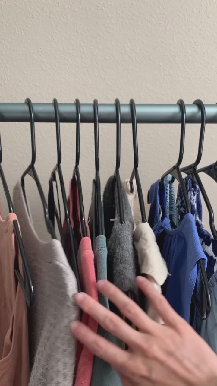 Hand browsing clothes on a closet rack.