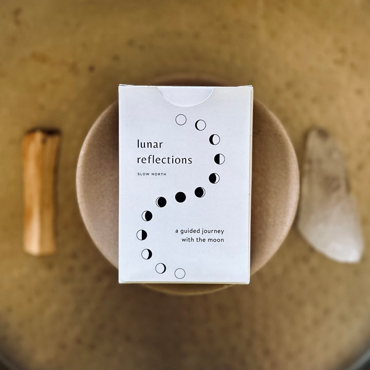 Lunar Reflections Mindfulness Cards box with moon phase design, surrounded by natural items, for enhancing mindfulness.