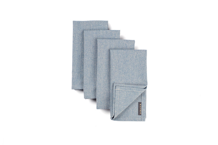 Set of four soft cotton cloth napkins in natural colors laid on wooden table for sustainable dining