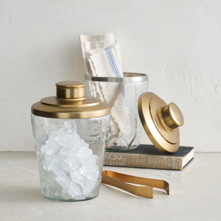 Pebbled glass ice bucket with brushed brass tongs and hammered brass lid for cocktail serving