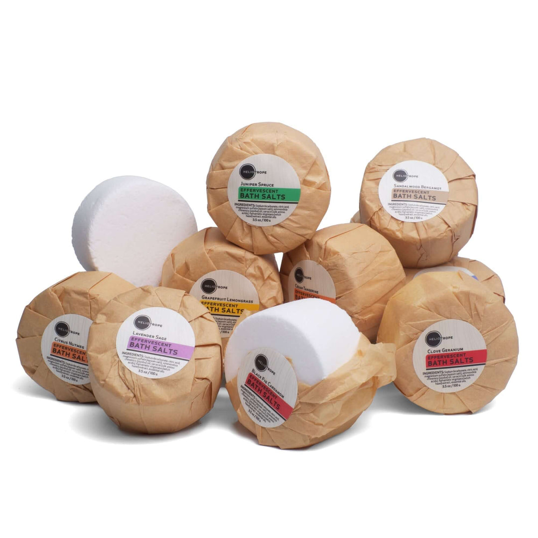 Collection of effervescent bath fizzies with jojoba oil and silk proteins wrapped in biodegradable paper for a zero-waste bath experience.