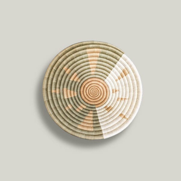 Handwoven sisal basket with natural brown and green patterns made by refugee artisans using traditional coil weaving