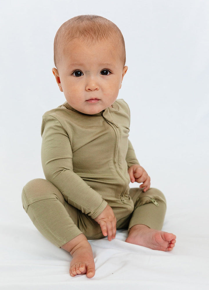 Baby wearing Luxe Bamboo Baby Pajamas in Moss Green, showcasing soft, smooth, antimicrobial fabric with fold-over mittens and two-way zipper.