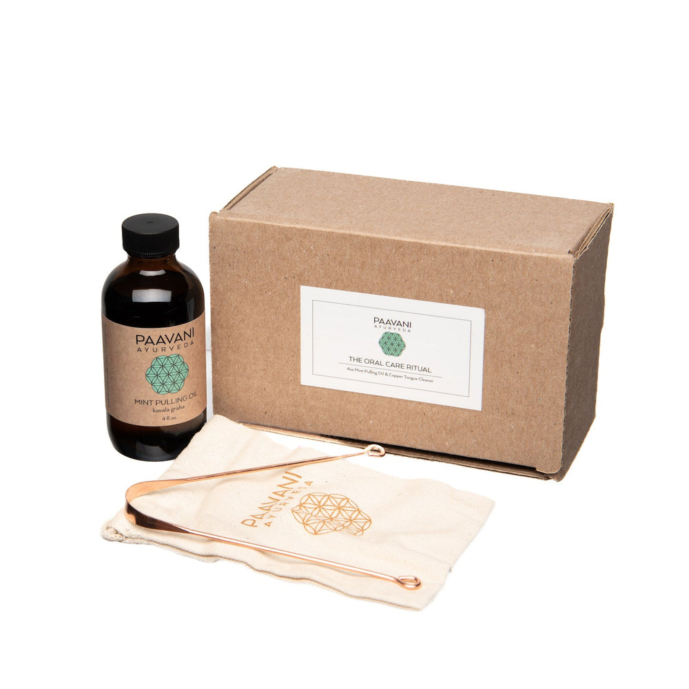 Ayurvedic oral care set with oil pulling bottle, tongue cleaner, and packaging for holistic dental health.
