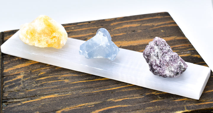 Polished white selenite crystal bar on natural surface showing smooth translucent mineral texture