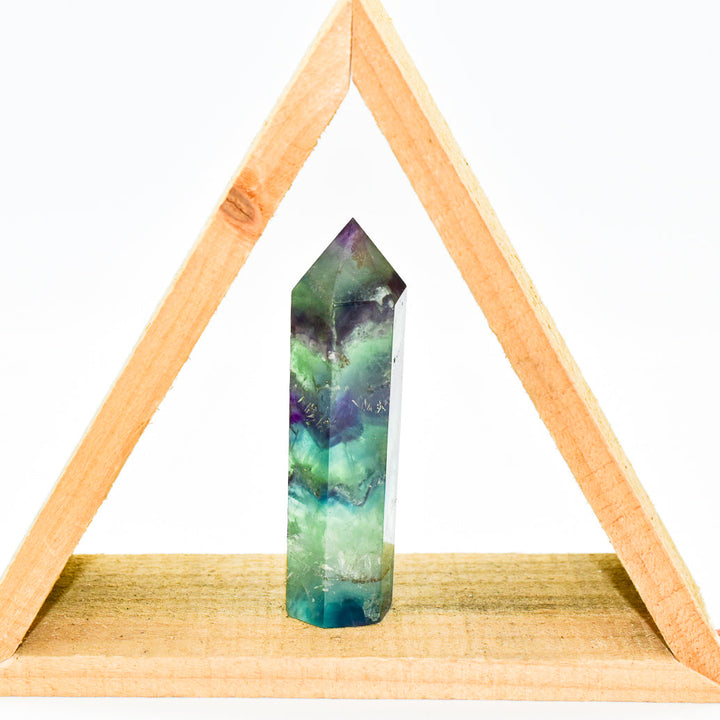 Hand cut polished fluorite crystal point with purple translucent color displaying natural stone variations