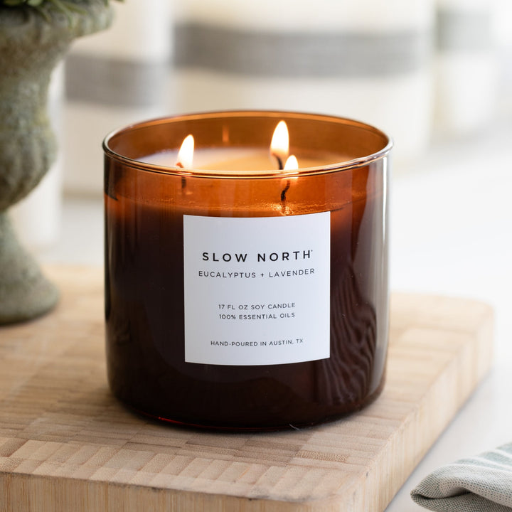 Natural soy wax three-wick candle with eucalyptus lavender essential oil blend in glass jar on wooden surface