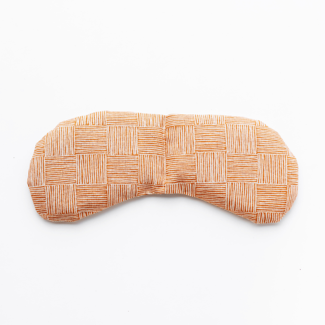 Weighted eye mask with checkered orange pattern for migraine relief and tension reduction.