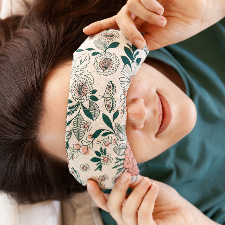Person relaxing with a weighted eye mask featuring a floral pattern, ideal for tension relief and migraine comfort.