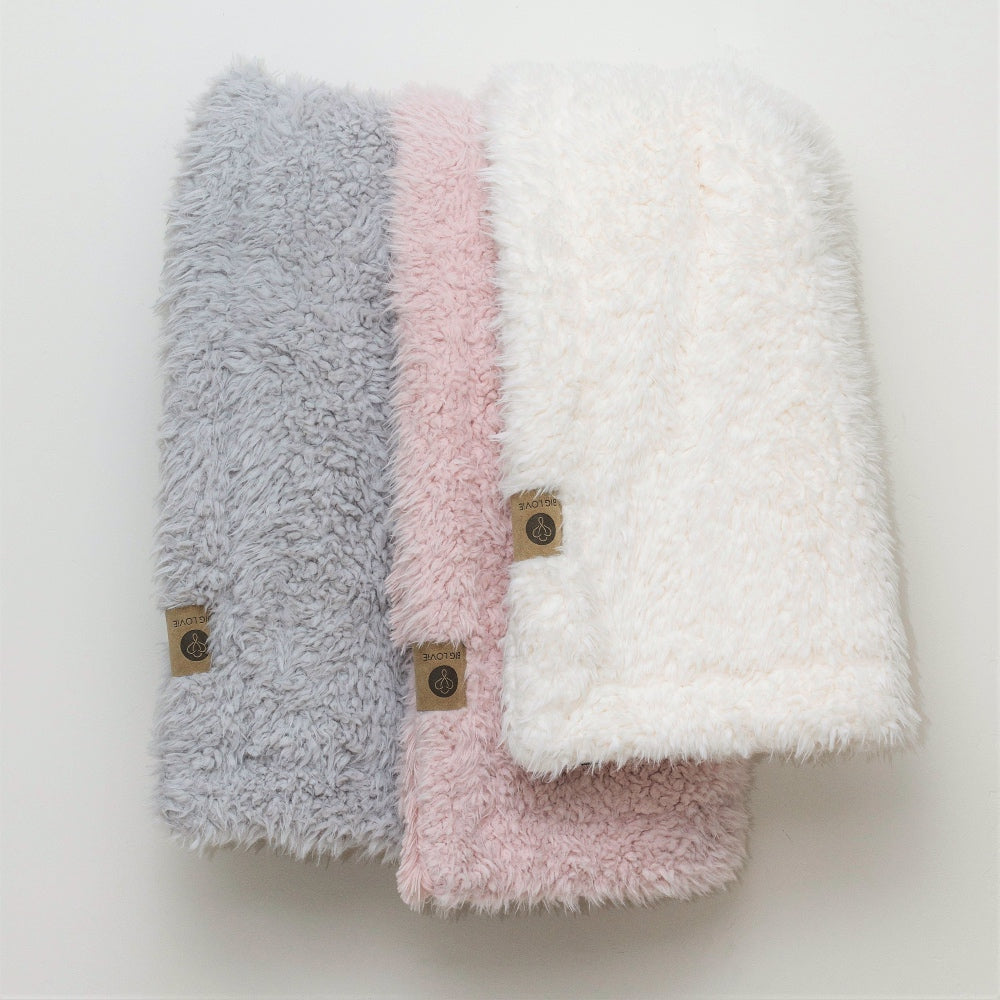 Three Angel Plush blankets in Silver, Pink, and Whisper White, showcasing their fluffy texture and luxurious softness. Perfect for cozy interiors.