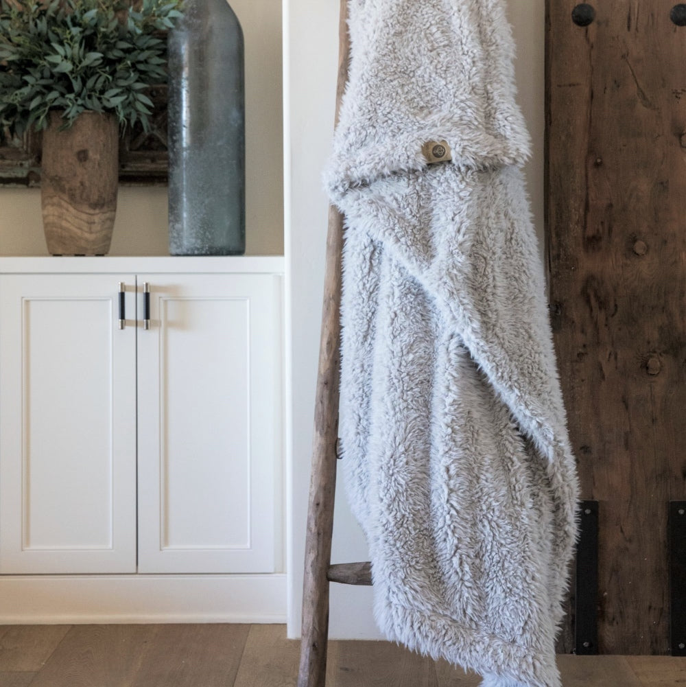 Cozy Angel Plush Blanket draped over a rustic ladder in a calming, neutral-colored room enhancing home decor ambiance.