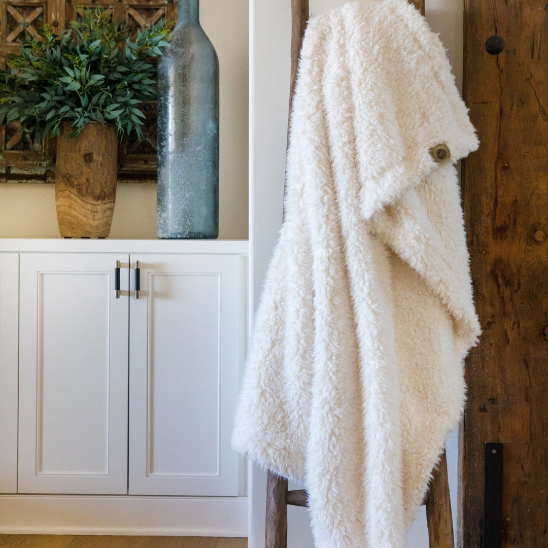 Cozy Angel Plush blanket draped on a rustic ladder in a stylish, serene home setting