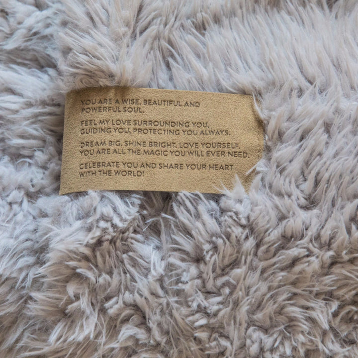 Close-up of Angel Plush blanket texture with a motivational message tag.