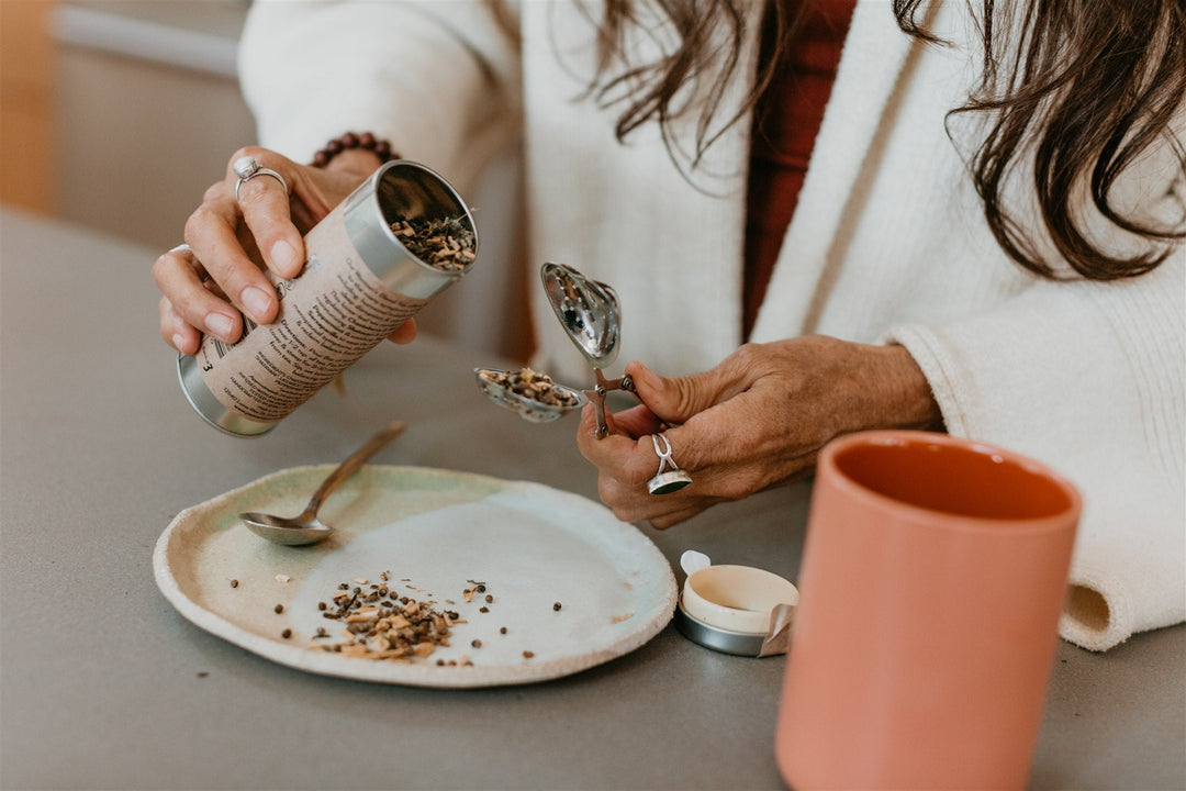 Woman preparing Ayurvedic tea from canister, showcasing Women's Blend herbal tea for hormonal balance and female support.