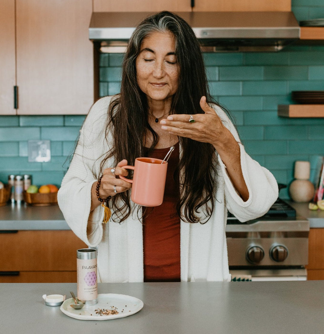 Woman enjoys Ayurvedic Women’s Blend tea for hormonal balance in a modern kitchen.