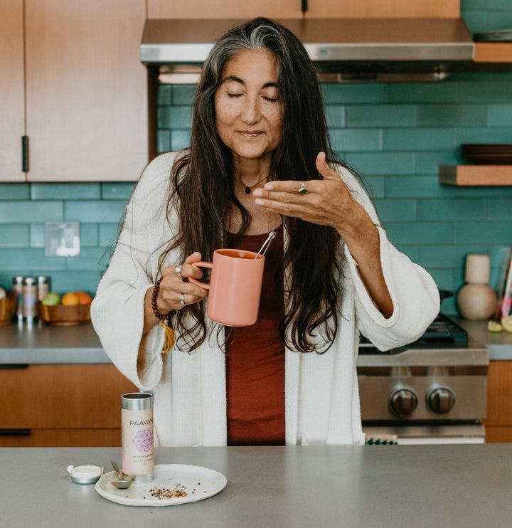 Woman enjoys Ayurvedic Women’s Blend tea for hormonal balance in a modern kitchen.