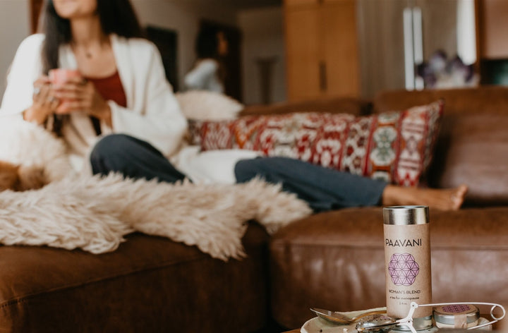 Woman enjoying Women's Blend Ayurvedic Tea for hormonal balance and cooling relief in a cozy living room setting.