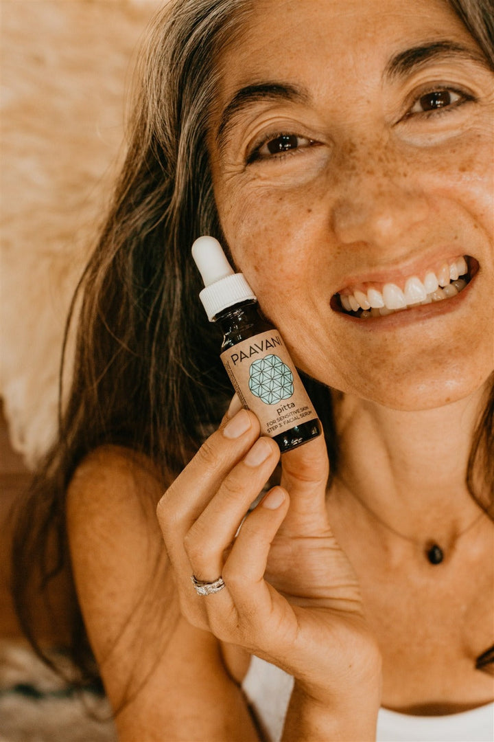 Woman holding a bottle of Paavani Pitta Skincare, highlighting ayurvedic skincare for sensitive skin, detox, and hydration.