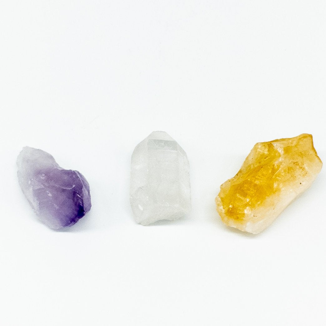 Set of 3 crystals: amethyst, citrine, and quartz on white background for energy healing and spiritual wellness.