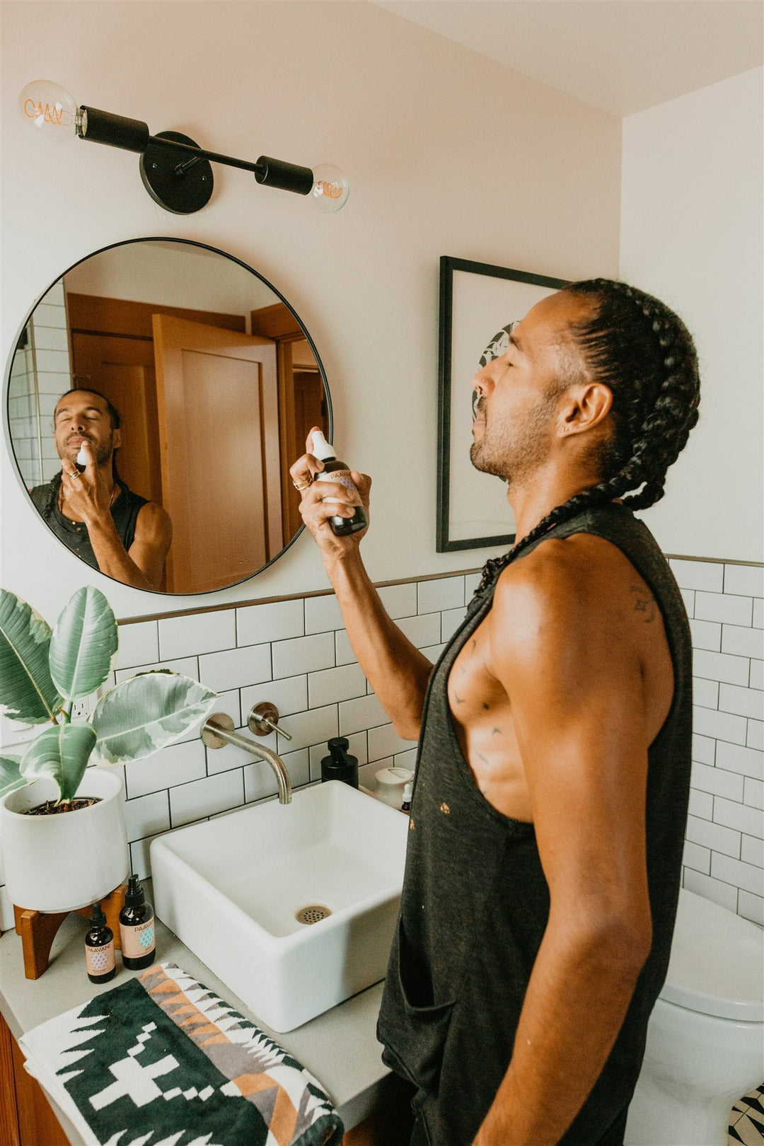 Man applying skincare product from the Pitta Skincare Ritual collection in a modern bathroom setting.