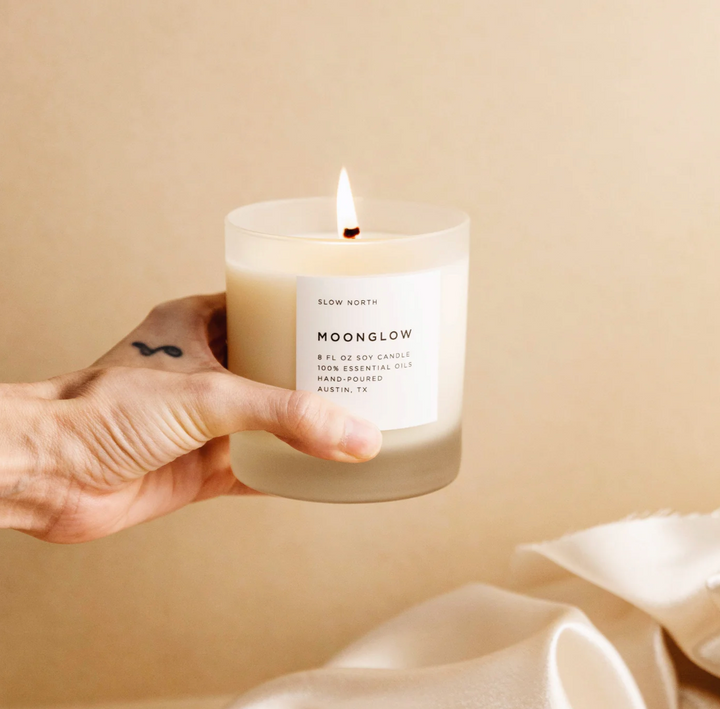 Hand holding Slow North Moonglow candle with warm glow, part of the Calming Rituals Collection - Gift Bundle for relaxation.