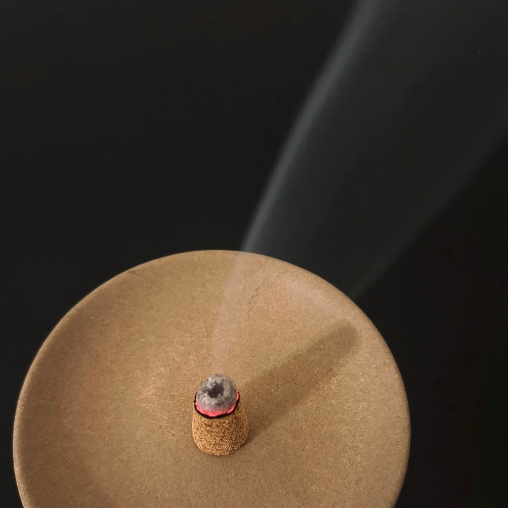 Palo Santo incense cone burning on a dish from the Calming Rituals Collection Gift Bundle, emitting soothing aroma for relaxation.