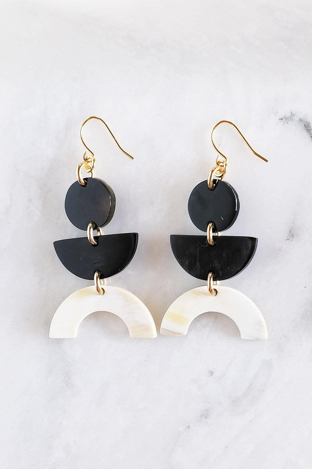 Vui Mung geometric buffalo horn earrings in light and dark horn with gold-plated hooks, handcrafted and chemical-free, displayed on a marble surface.